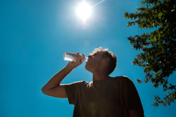 太陽の下水を飲む男性