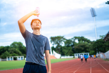 グラウンドで水をかぶる男性
